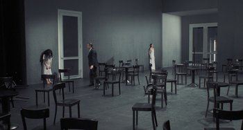 Movie still from “Pina” (2011), directed by Wim Wenders – Two men are standing in an empty room with chairs; Extreme Wide shot, High angle