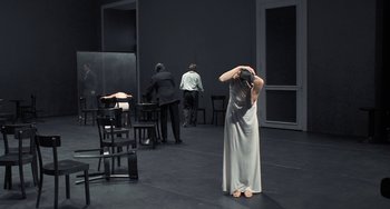 Movie still from “Pina” (2011), directed by Wim Wenders – A woman standing in front of two men in an empty room; Wide shot, High angle