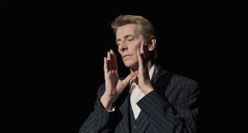Movie still from “Pina” (2011), directed by Wim Wenders – A man in pinstriped suit praying with his eyes closed; Close Up shot, Low angle