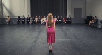 Movie still from “Pina” (2011), directed by Wim Wenders – A woman in a pink dress standing in front of a group of people; Wide shot, High angle
