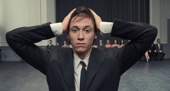 Movie still from “Pina” (2011), directed by Wim Wenders – A man in a suit and tie holding his head; Close Up shot, Low angle