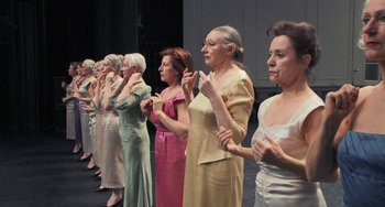 Movie still from “Pina” (2011), directed by Wim Wenders – A group of older women standing on a stage clapping; Medium shot, Low angle