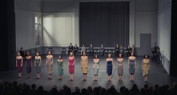 Movie still from “Pina” (2011), directed by Wim Wenders – A group of women standing on a stage in front of an audience; Wide shot, High angle