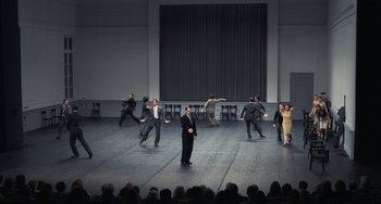 Movie still from “Pina” (2011), directed by Wim Wenders – A group of men and women dancing on a stage in front of an audience; Extreme Wide shot, High angle