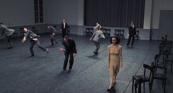 Movie still from “Pina” (2011), directed by Wim Wenders – A group of men and a woman dancing on a stage; Wide shot, High angle
