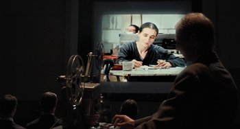 Movie still from “Pina” (2011), directed by Wim Wenders – A person sitting in front of a projector screen; Medium shot, Over the shoulder angle