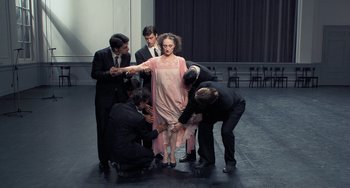 Movie still from “Pina” (2011), directed by Wim Wenders – A group of people standing around a woman in a pink dress; Wide shot, High angle