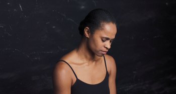 Movie still from “Pina” (2011), directed by Wim Wenders – A woman in a black tank top is looking down; Close Up shot, Low angle