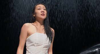 Movie still from “Pina” (2011), directed by Wim Wenders – A woman in a white dress standing in the rain; Medium shot, Low angle