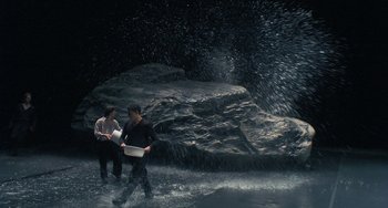 Movie still from “Pina” (2011), directed by Wim Wenders – Two men are walking in the water with a laptop in their hands; Wide shot, High angle