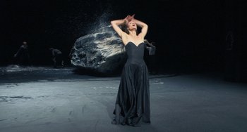 Movie still from “Pina” (2011), directed by Wim Wenders – A woman in a long black dress standing in front of a rock; Medium shot, Low angle