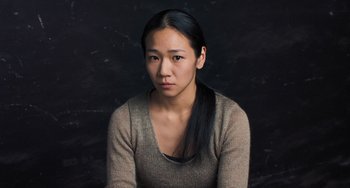 Movie still from “Pina” (2011), directed by Wim Wenders – A woman with long black hair sitting in front of a black background; Close Up shot, High angle