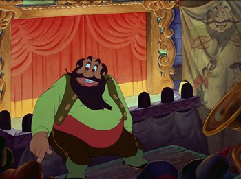 Movie still from “Pinocchio” (1940), directed by Jack Kinney – A man with a beard is sitting on a stage in front of an audience; Medium shot, Low angle