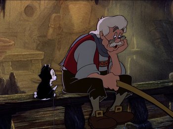 Movie still from “Pinocchio” (1940), directed by Jack Kinney – An old man sitting next to a black and white cat; Wide shot, Low angle