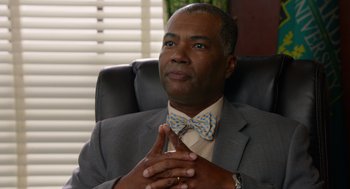 Movie still from “Pitch Perfect 2” (2015), directed by Elizabeth Banks – A man sitting in a chair with his hands clasped together; Close Up shot, Over the shoulder angle