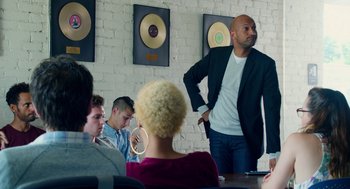 Movie still from “Pitch Perfect 2” (2015), directed by Elizabeth Banks – A group of people sitting around a table; Medium shot, Over the shoulder angle