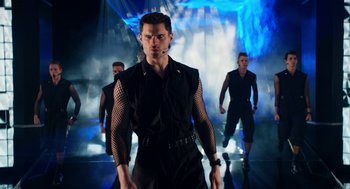 Movie still from “Pitch Perfect 2” (2015), directed by Elizabeth Banks – A group of men are walking on a stage; Medium shot, Low angle