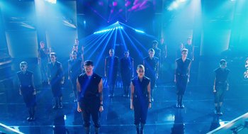 Movie still from “Pitch Perfect 2” (2015), directed by Elizabeth Banks – A group of people standing on a stage in front of lights; Wide shot, High angle