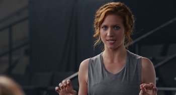 Movie still from “Pitch Perfect 2” (2015), directed by Elizabeth Banks – A woman with red hair is holding a stick; Close Up shot, Over the shoulder angle