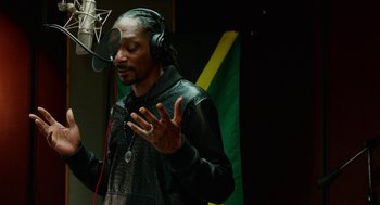 Movie still from “Pitch Perfect 2” (2015), directed by Elizabeth Banks – A man wearing headphones and singing into a microphone; Medium shot, Low angle