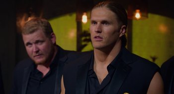Movie still from “Pitch Perfect 2” (2015), directed by Elizabeth Banks – A man in a black suit stands next to another man in a black suit; Close Up shot, Low angle