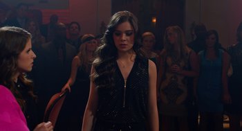 Movie still from “Pitch Perfect 2” (2015), directed by Elizabeth Banks – A woman in a black dress standing in front of a group of people; Medium shot, Over the shoulder angle