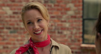 Movie still from “Pitch Perfect 2” (2015), directed by Elizabeth Banks – A woman wearing a red neck scarf smiling for the camera; Close Up shot, Over the shoulder angle
