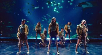 Movie still from “Pitch Perfect 3” (2017), directed by Trish Sie – A group of people standing in front of an aquarium; Wide shot, High angle
