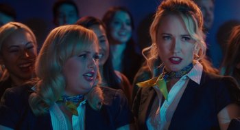 Movie still from “Pitch Perfect 3” (2017), directed by Trish Sie – A group of women standing next to each other in a room; Close Up shot, Over the shoulder angle