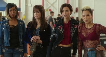 Movie still from “Pitch Perfect 3” (2017), directed by Trish Sie – Two young women are walking together while holding a guitar; Medium shot, Over the shoulder angle