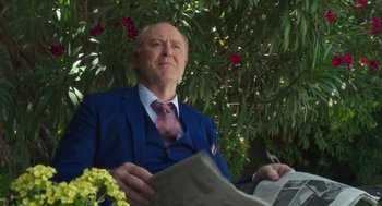 Movie still from “Pitch Perfect 3” (2017), directed by Trish Sie – An older man in a blue suit and a red neck tie; Medium shot, Low angle