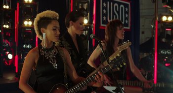 Movie still from “Pitch Perfect 3” (2017), directed by Trish Sie – A group of women playing instruments in front of a microphone; Medium shot, Low angle