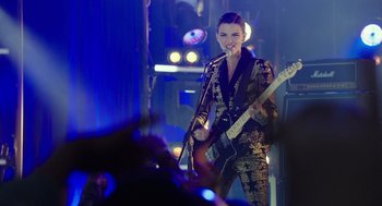 Movie still from “Pitch Perfect 3” (2017), directed by Trish Sie – A woman holding a guitar in front of a crowd; Medium shot, Over the shoulder angle