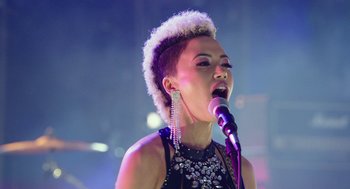 Movie still from “Pitch Perfect 3” (2017), directed by Trish Sie – A woman is singing into a microphone on a stage; Close Up shot, Low angle