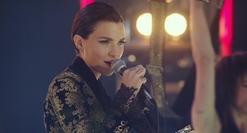 Movie still from “Pitch Perfect 3” (2017), directed by Trish Sie – A woman is singing into a microphone in front of lights; Close Up shot, Over the shoulder angle