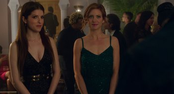 Movie still from “Pitch Perfect 3” (2017), directed by Trish Sie – A woman in a green dress standing next to another woman in a black dress; Medium shot, Over the shoulder angle
