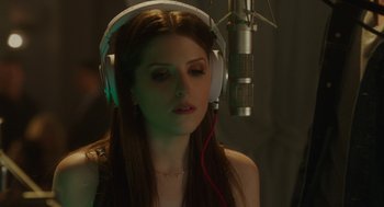 Movie still from “Pitch Perfect 3” (2017), directed by Trish Sie – A woman wearing headphones in front of a microphone; Close Up shot, Over the shoulder angle
