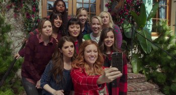 Movie still from “Pitch Perfect 3” (2017), directed by Trish Sie – A woman taking a selfie with a group of women; Wide shot, Overhead angle