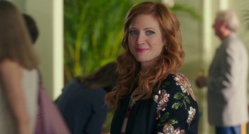 Movie still from “Pitch Perfect 3” (2017), directed by Trish Sie – A woman with long red hair wearing a floral jacket; Close Up shot, Over the shoulder angle