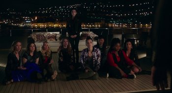 Movie still from “Pitch Perfect 3” (2017), directed by Trish Sie – A group of people sitting on a deck at night; Wide shot, High angle