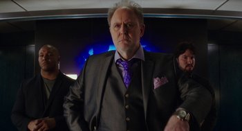 Movie still from “Pitch Perfect 3” (2017), directed by Trish Sie – A man in a suit and tie standing next to another man in a suit and tie; Medium shot, Low angle