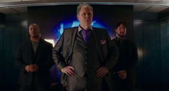 Movie still from “Pitch Perfect 3” (2017), directed by Trish Sie – A man standing next to two other men in a suit; Medium shot, Low angle