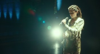 Movie still from “Pitch Perfect 3” (2017), directed by Trish Sie – A woman holding a microphone in a dark room; Medium shot, High angle