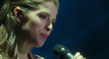 Movie still from “Pitch Perfect 3” (2017), directed by Trish Sie – A person holding a microphone; Close Up shot, Over the shoulder angle