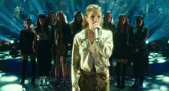 Movie still from “Pitch Perfect 3” (2017), directed by Trish Sie – A group of women standing in front of a microphone; Medium shot, Overhead angle
