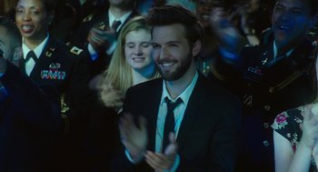 Movie still from “Pitch Perfect 3” (2017), directed by Trish Sie – A man in a black suit clapping in front of a crowd; Close Up shot, Over the shoulder angle