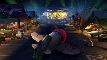 Movie still from “Planes” (2013), directed by Klay Hall – An inflatable airplane is in a street near a stage; Extreme Wide shot, High angle