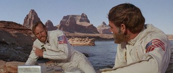 Movie still from “Planet of the Apes” (1968), directed by Franklin J. Schaffner – A man sitting next to a body of water; Medium shot, Over the shoulder angle