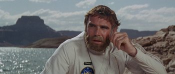 Movie still from “Planet of the Apes” (1968), directed by Franklin J. Schaffner – A man with long hair and a beard is wearing a white jacket; Close Up shot, Over the shoulder angle
