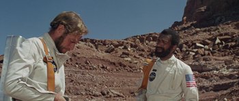 Movie still from “Planet of the Apes” (1968), directed by Franklin J. Schaffner – A man and a woman are standing on a rocky surface; Medium shot, Low angle